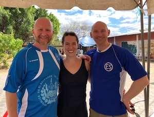 Dr. Jennifer McNamara pictured with her arms around two friends on a sunny day